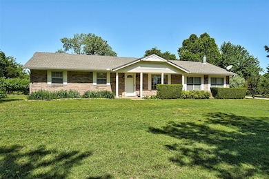 Ranch-style home featuring a front yard, covered porch, and brick siding