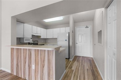 Kitchen featuring under cabinet range hood, light countertops, a peninsula, light wood-style floors, and white appliances