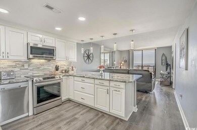 Kitchen with appliances with stainless steel finishes, light stone countertops, a peninsula, white cabinets, and recessed lighting