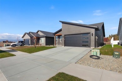 Contemporary home featuring driveway, an attached garage, and a front lawn