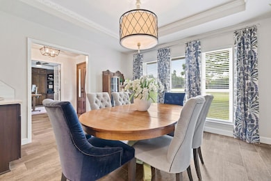 Dining room with a tray ceiling, a chandelier, li