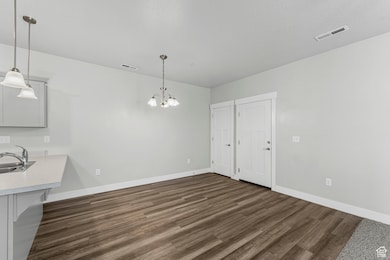 Unfurnished dining area with dark wood-type flooring and a chandelier