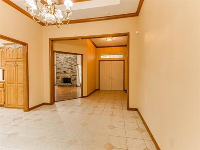Corridor featuring brick wall, a chandelier, ornamental molding, and light tile flooring