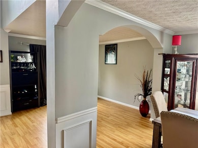 Hall featuring arched walkways, wood finished floo