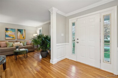 Foyer entrance featuring ornate columns, wood-type flooring, and crown molding