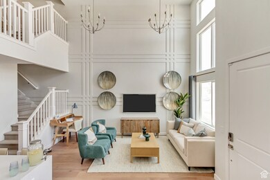 PHOTO FROM SIMILAR MODEL HOME. COLORS, OPTIONS, AND FEATURES WILL VARY: Living room with stairs, plenty of natural light, wood finished floors, a towering ceiling, and a chandelier
