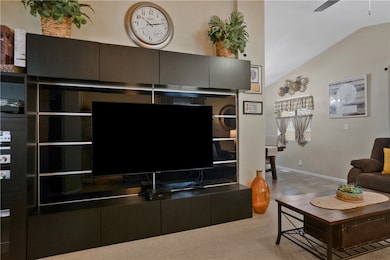 Living room featuring vaulted ceiling, light colored carpet, and ceiling fan