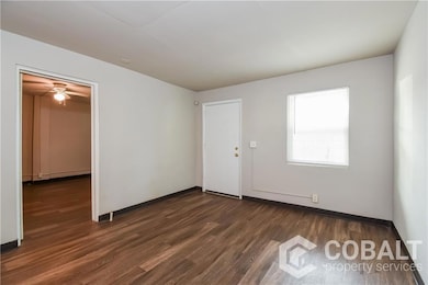 Empty room with dark wood-style flooring and ceiling fan
