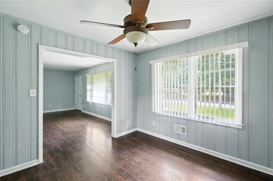 Unfurnished room featuring wood finished floors, ceiling fan, a smoke detector, and a decorative wall