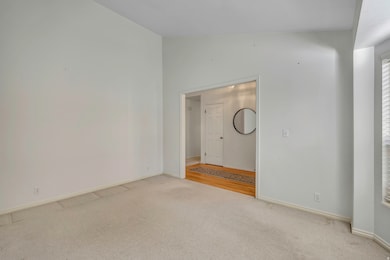 Empty room with carpet flooring and vaulted ceiling