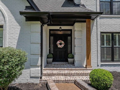 Entrance to property featuring brick siding and a shingled roof