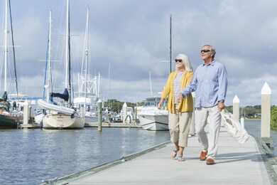 Happy-senior-couple-walking-along-harbor