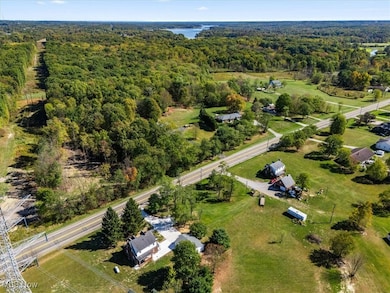 Aerial view of property and surrounding area featuring a nearby body of water and a forest