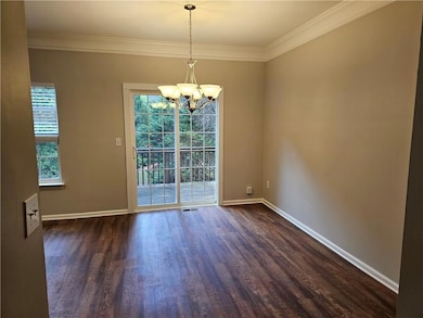 Unfurnished room with dark wood finished floors, a chandelier, crown molding, and baseboards