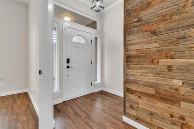 Entryway with ornamental molding, wood finished floors, and wood walls