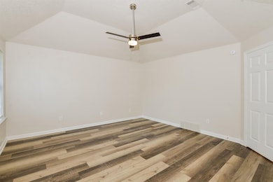 Unfurnished room featuring vaulted ceiling, wood finished floors, and a ceiling fan