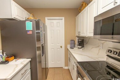 Kitchen featuring white cabinets, light tile patte