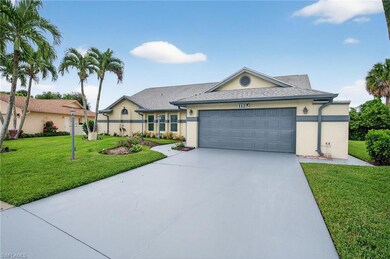 Single story home featuring a front lawn, driveway, stucco siding, and an attached garage