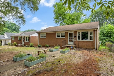 Rear view of house featuring a garden and brick si