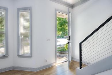 Entryway featuring wood finished floors, baseboards, and ornamental molding