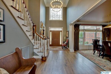 Two Story Foyer enhanced with warm hardwood floors, gorgeous crown moulding, decorator colors