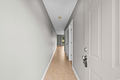 Corridor with light tile patterned flooring and baseboards