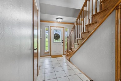 Entryway featuring crown molding, baseboards, light tile patterned floors, a textured wall, and stairway