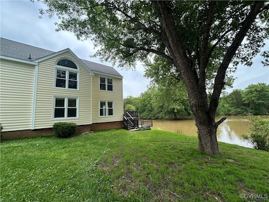 View of grassy yard with a deck with water view