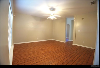 Empty room featuring dark wood-style flooring and ceiling fan