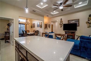 Kitchen featuring coffered ceiling, hanging light fixtures, open floor plan, a chandelier, and a kitchen island
