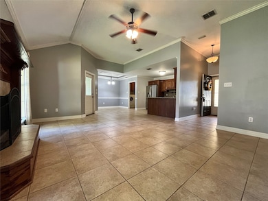 Unfurnished living room featuring ceiling fan, ornamental molding, a fireplace with raised hearth, light tile patterned flooring, and a chandelier
