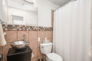Full bath featuring tile walls, vanity, and curtained shower
