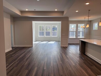 Unfurnished living room with a raised ceiling, dark wood-type flooring, and a notable chandelier