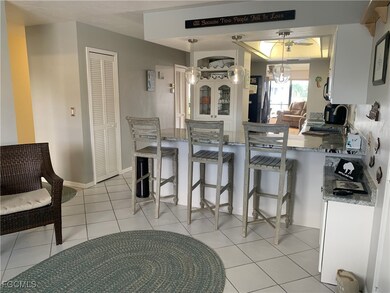 Kitchen with kitchen peninsula, light tile patterned floors, decorative light fixtures, and stainless steel refrigerator