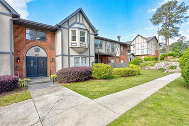 Tudor house with stucco siding, a front yard, and brick siding