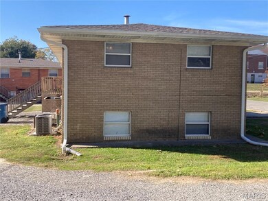 View of side of home featuring brick siding, a lawn, a deck, and stairway