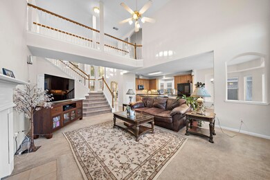 Spacious living room with high ceilings, grand staircase, and open floor plan.