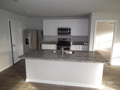 Kitchen featuring light stone countertops, stainless steel appliances, white cabinets, and dark wood finished floors