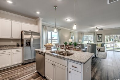 Kitchen featuring stainless steel appliances, a sink, ornamental molding, open floor plan, and dark wood-type flooring