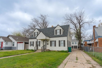 New england style home with roof with shingles, driveway, a garage, and a chimney