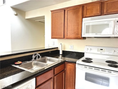 Kitchen featuring white appliances, dark stone cou