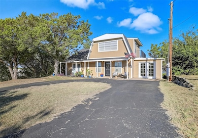 View of front of property featuring a front yard, stucco siding, french doors, and driveway