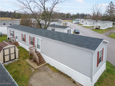 View of front facade featuring a storage shed, roof with shingles, and a residential view