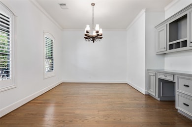 Just off the entry, the study features rich hardwood floors, two arched windows with plantation shutters, and elegant crown molding. Fresh paint and a custom built-in desk with drawers and shelving complete this light-filled and functional space.