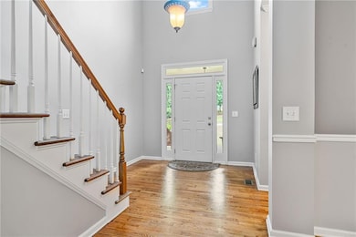 Foyer with healthy amount of natural light, a towering ceiling, wood finished floors, and stairs