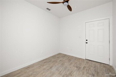 Empty room featuring light wood finished floors, visible vents, baseboards, and ceiling fan