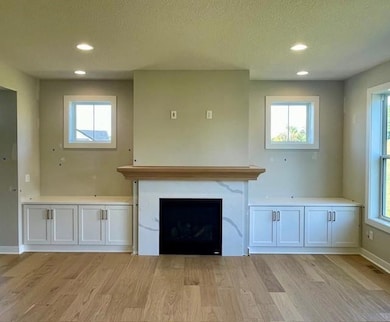 Spacious main floor Gathering Room with oversized windows and fireplace flanked by custom built in cabinets.