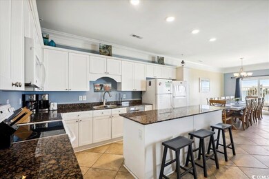 Kitchen featuring white appliances, visible vents, a kitchen island, white cabinetry, and a sink