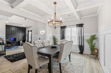 Dining area with coffered ceiling, a chandelier, healthy amount of natural light, a decorative wall, and beamed ceiling