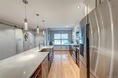 Kitchen with stainless steel appliances, pendant lighting, light wood finished floors, glass insert cabinets, and  center island